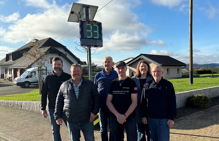 Des habitants de la commune de Preisheid et des installateurs de l'entreprise Westenergie devant un radar pédagogique EVOLIS Vision installé dans un quartier résidentiel.