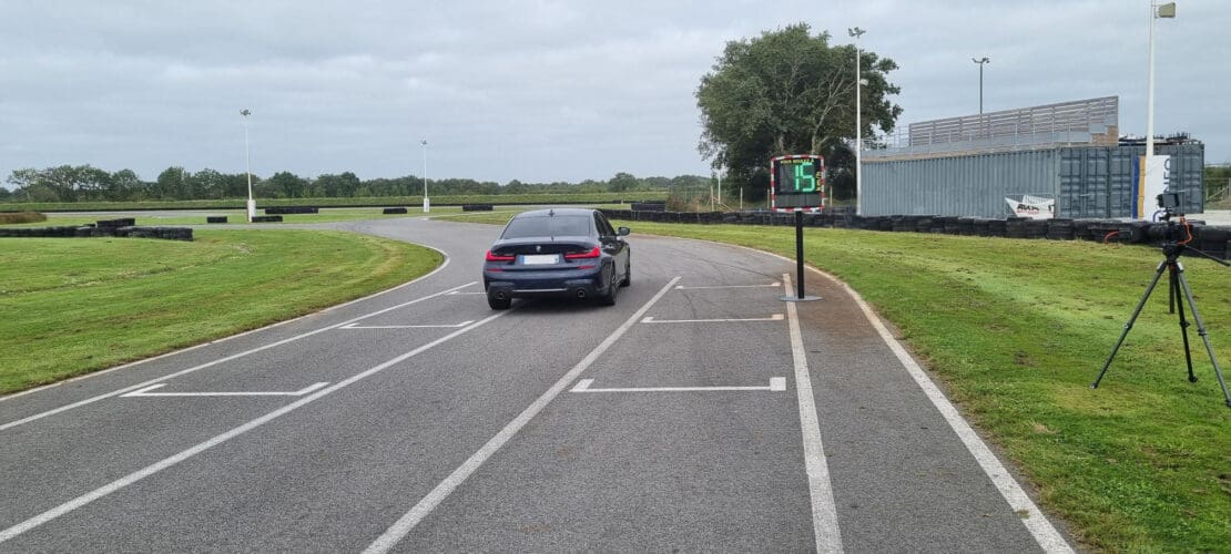 Un coche circula en una pista de karts mientras el radar pedagógico EVOLIS mide la velocidad.